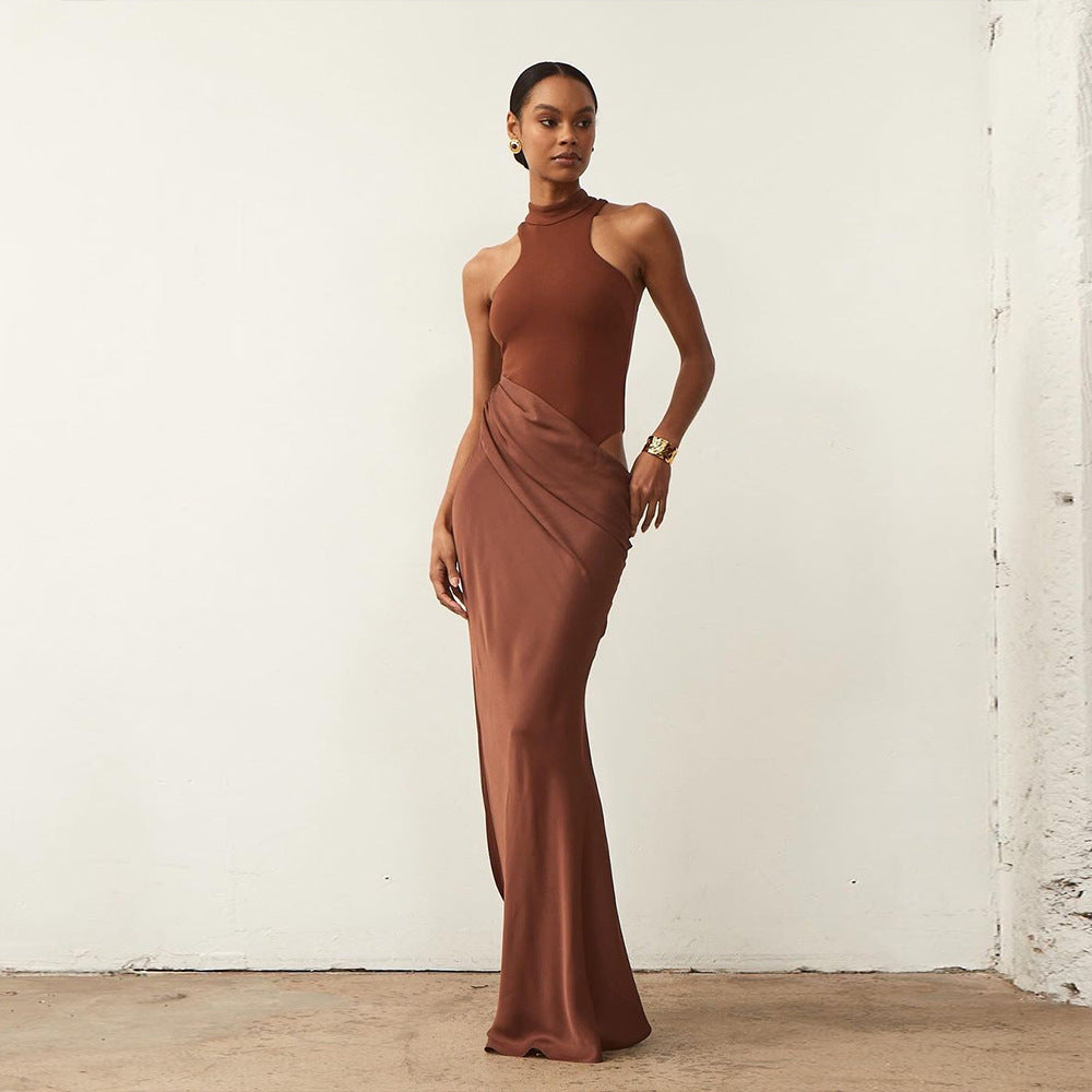 Elegant brown floor-length dress with halter neckline, fitted bodice, and draped skirt, worn by a model standing against a white textured wall