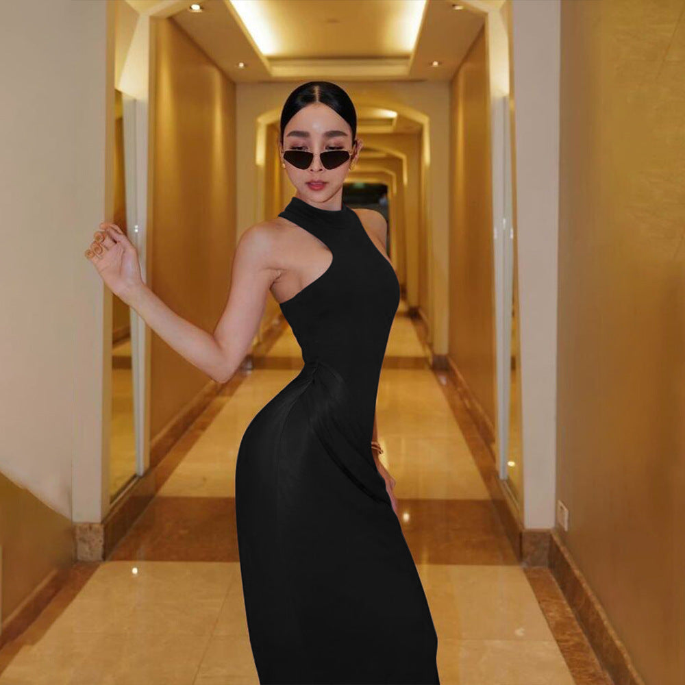 Sleek black halter-neck dress with sunglasses, worn by a model posing in a golden-toned hallway with perspective lines