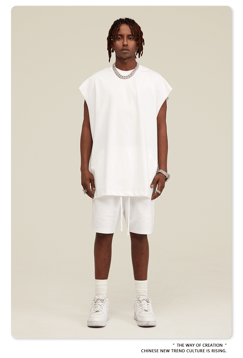 Male model in crisp white two-piece set with oversized sleeveless top and drawstring shorts with silver chain