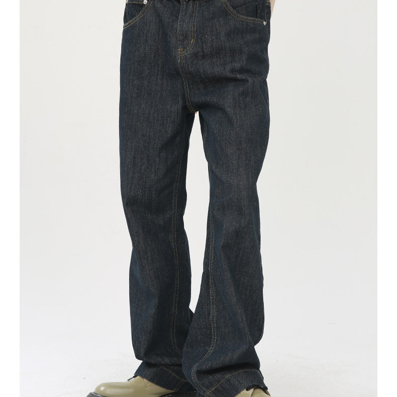 A model is wearing dark indigo wide-leg jeans with a beige sweater and decorative metal belt buckle, standing in olive platform shoes
