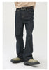 A model is wearing dark indigo wide-leg jeans with a beige sweater and decorative metal belt buckle, standing in olive platform shoes