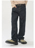 A model is standing with hand in pocket wearing raw denim wide-leg jeans, beige sweater, ornate metal buckle belt and olive platform shoes