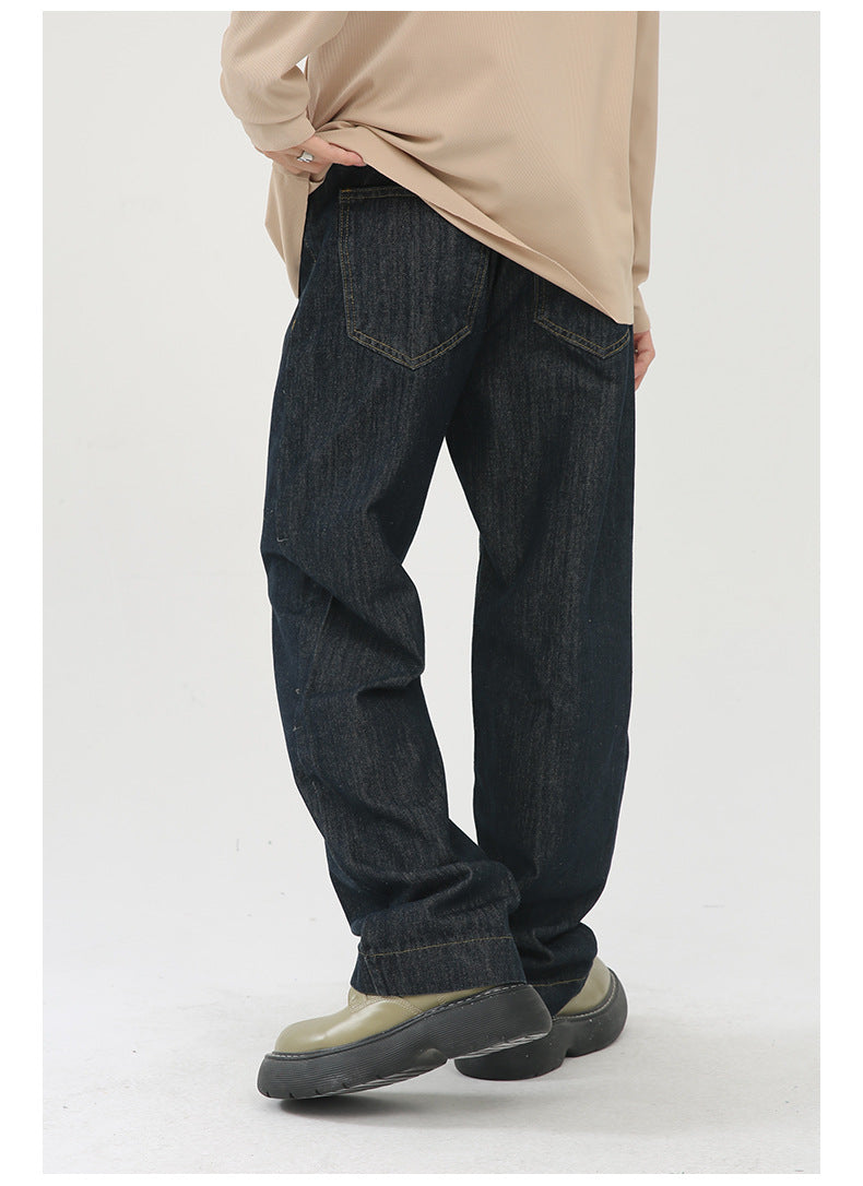 A model is standing in profile wearing dark straight-leg jeans with beige oversized top and olive platform boots against white background