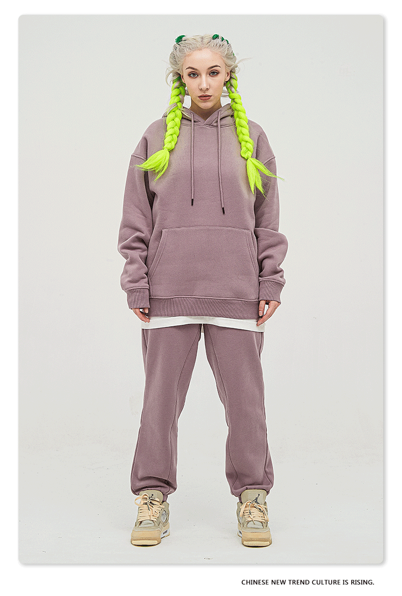 Model with platinum hair and neon yellow braids wearing a lilac purple sweatsuit with oversized hoodie and matching joggers