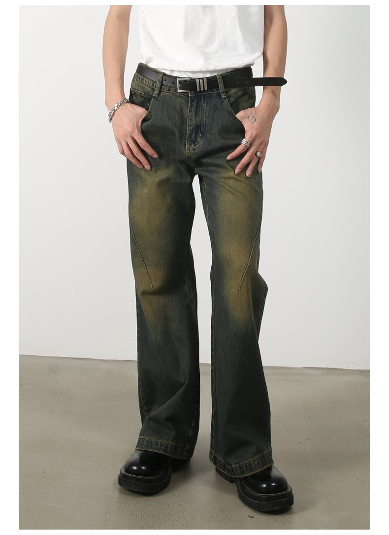 Front view of olive-green wide-leg jeans with unique seam detail and faded wash pattern, styled with white tank top and black belt