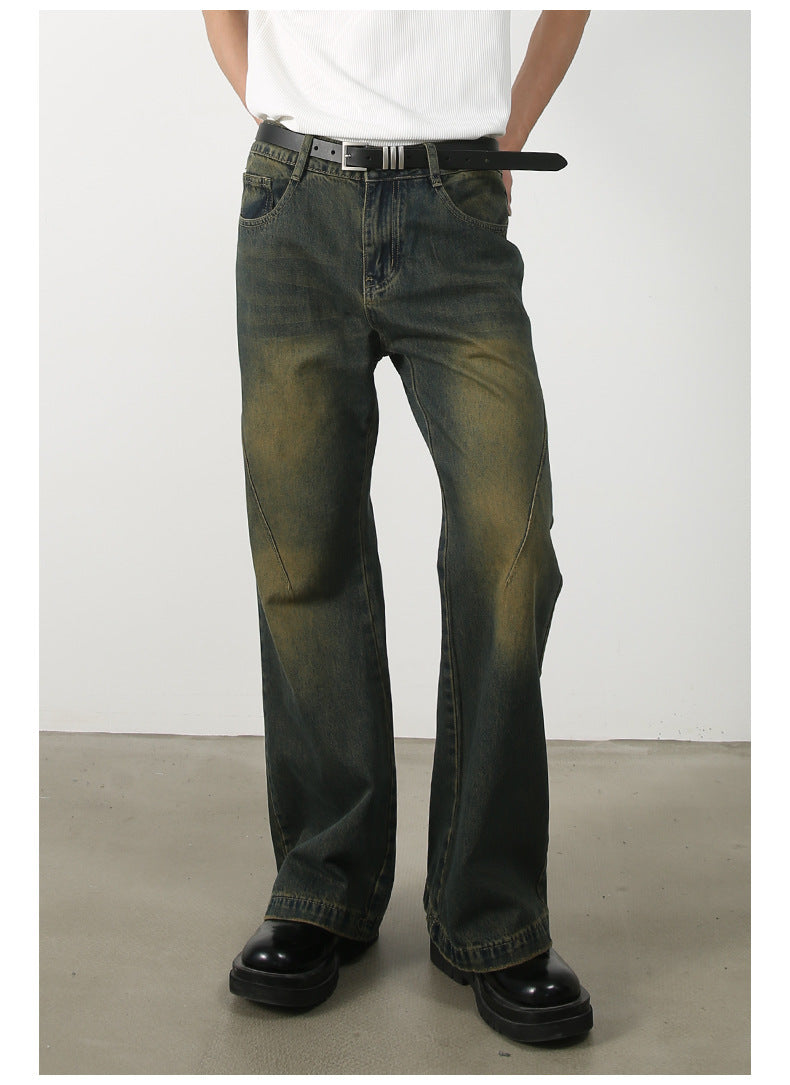 Full-length front view of olive-green wide-leg jeans with diagonal seam details and vintage wash styling, paired with black belt
