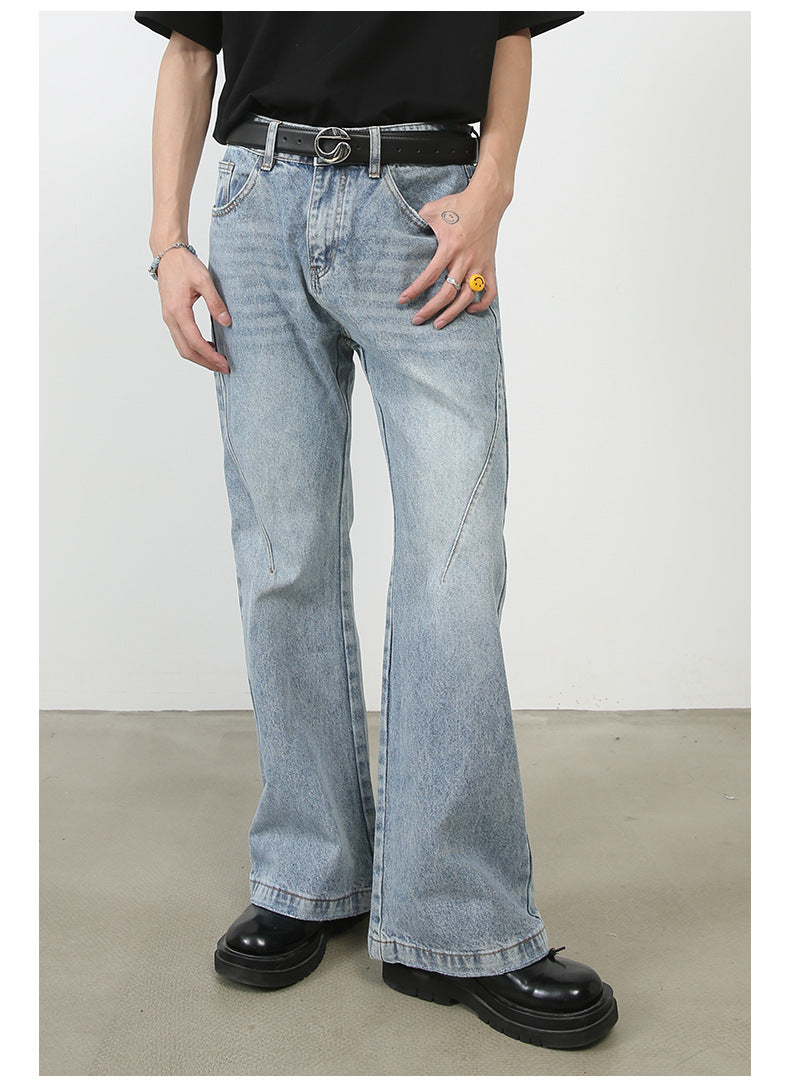 Model wearing light blue wide-leg jeans with unique seam details and faded pattern, styled with black t-shirt and circular logo belt