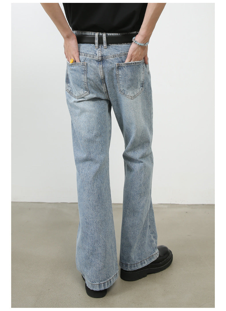 Rear view of light wash denim wide-leg jeans showing pocket placement and seam details, styled with black t-shirt and designer belt