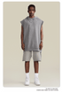 A model wearing light gray sleeveless hoodie with matching shorts, beaded necklace and white sneakers against neutral background
