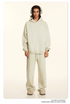 Model in off-white hoodie and sweatpants with silver headphones and cream slip-on shoes