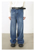 Model in white top with black belt and medium-wash wide-leg jeans paired with black shoes
