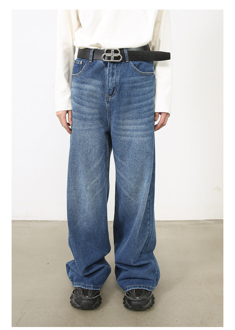 Model in white top with black belt and medium-wash wide-leg jeans paired with black shoes