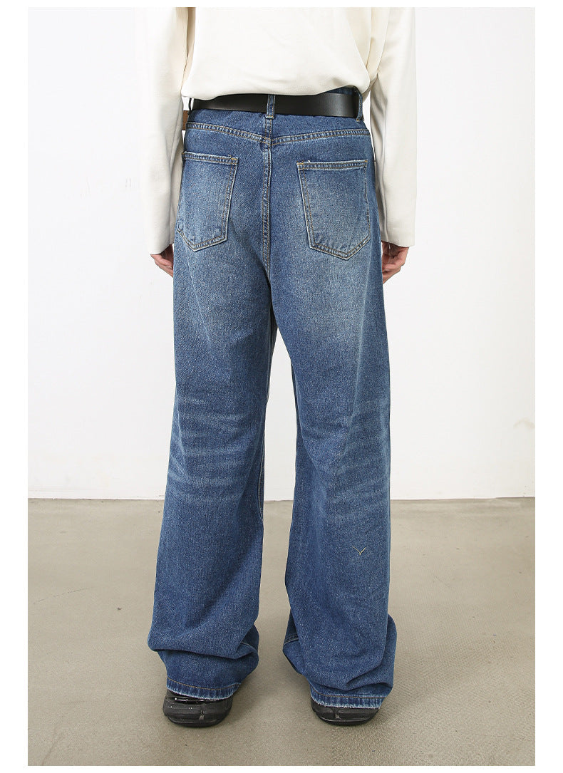 Back view of model in long-sleeve white top and wide-leg medium-wash jeans with black belt and shoes