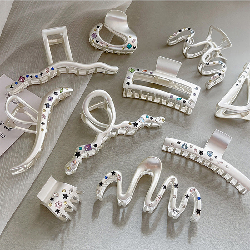 Assortment of white decorative hair clips laid flat, featuring various designs with crystal and star accents
