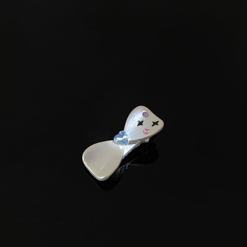 Pearl white hair clip with star and crystal embellishments on black surface