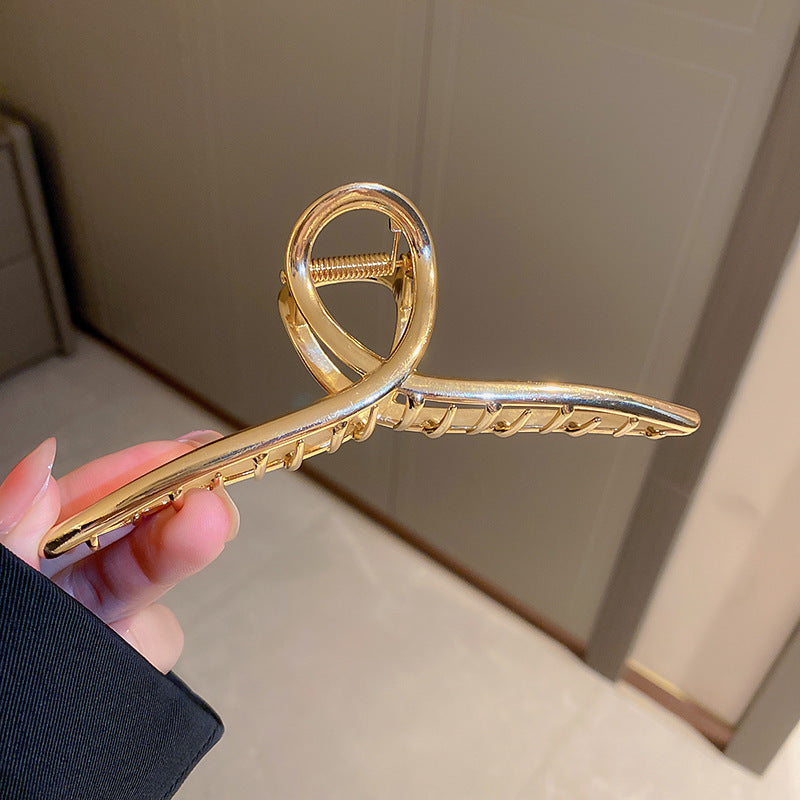 Gold-toned curved hair clip with textured grip design
