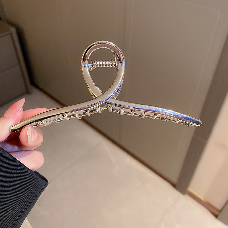 Silver-toned curved hair clip with spring mechanism detail