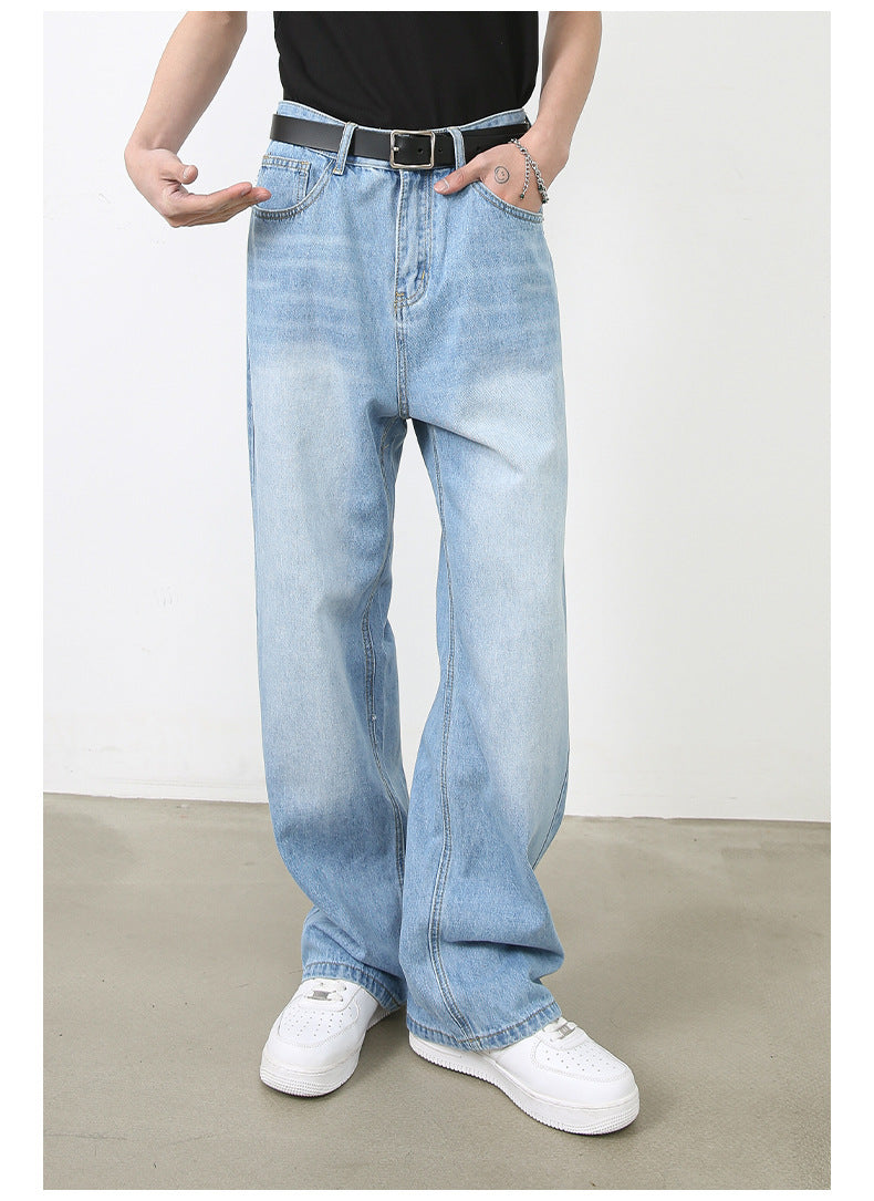A model is posing with hand in pocket wearing light wash wide-leg jeans, black top and belt against white backdrop