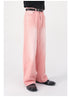 Side view of model in pink wide-leg denim pants with black belt, styled with black top and patent leather shoes