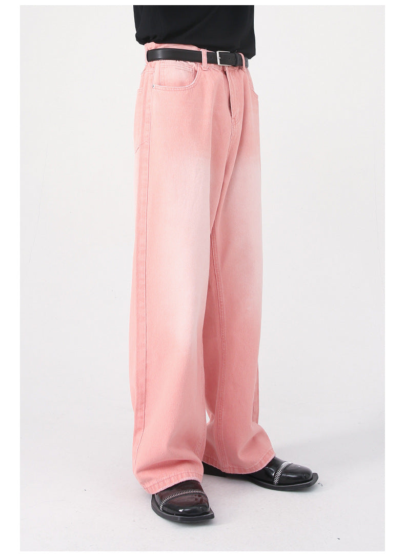 Side view of model in pink wide-leg denim pants with black belt, styled with black top and patent leather shoes