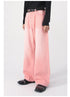 Front view of model wearing pink wide-leg jeans with diagonal seam detail, black belt and shiny black loafers