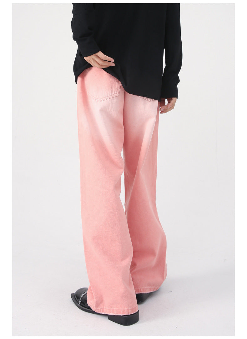 Rear view of model wearing pink loose denim jeans with black top and patent leather shoes against white background