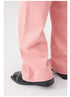 Close-up of pink denim wide-leg pant hem and cuff detail with black patent leather shoe visible