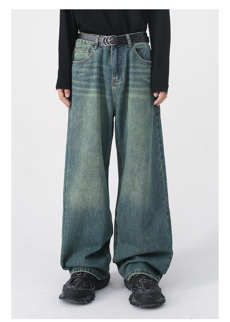 Model wearing faded green wide-leg jeans with black belt, black sweater and chunky black sneakers on light background
