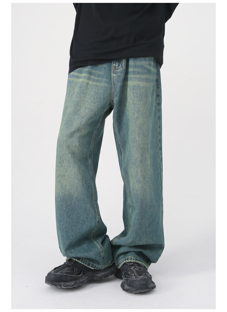 Side and front views of vintage-wash wide-leg green denim pants with black top and black chunky sneakers