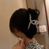 A woman in a leopard print top with her hair in a bun, secured by a rhinestone-decorated clip, photographed from behind