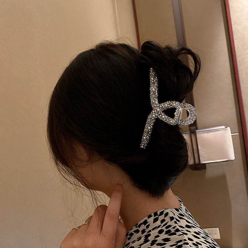 A woman in a leopard print top with her hair in a bun, secured by a rhinestone-decorated clip, photographed from behind