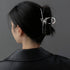 A woman in a black blazer wearing her hair in a bun secured with a silver butterfly hair stick, shown from behind