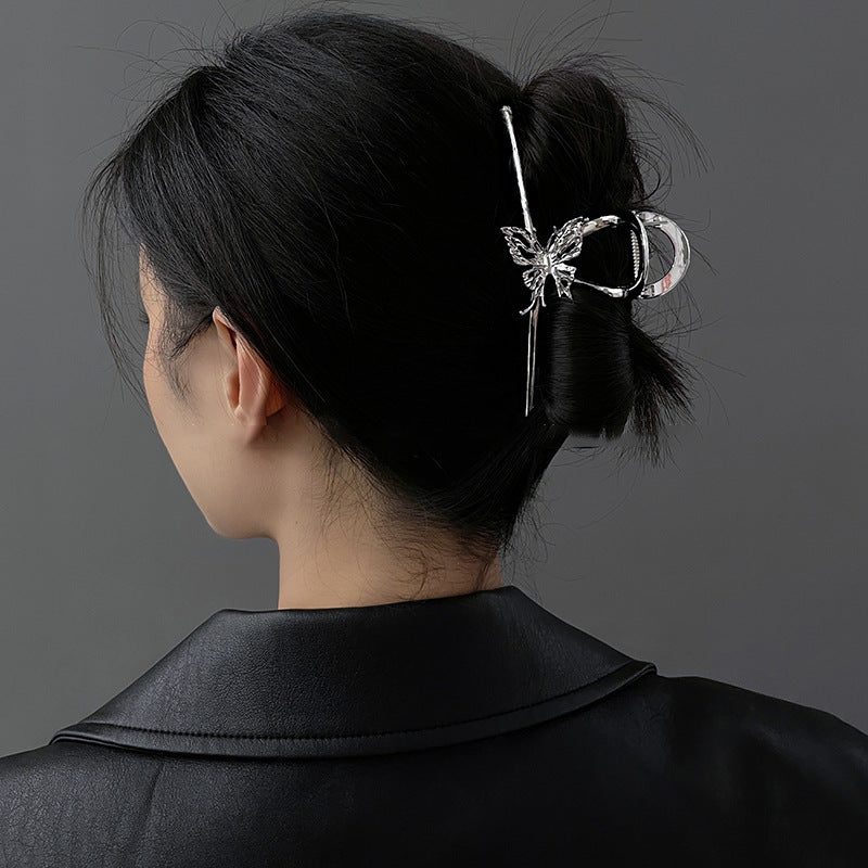 A woman in a black blazer wearing her hair in a bun secured with a silver butterfly hair stick, shown from behind