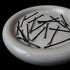 Black bobby pins scattered on white ceramic dish, minimalist hair accessories styling flatlay