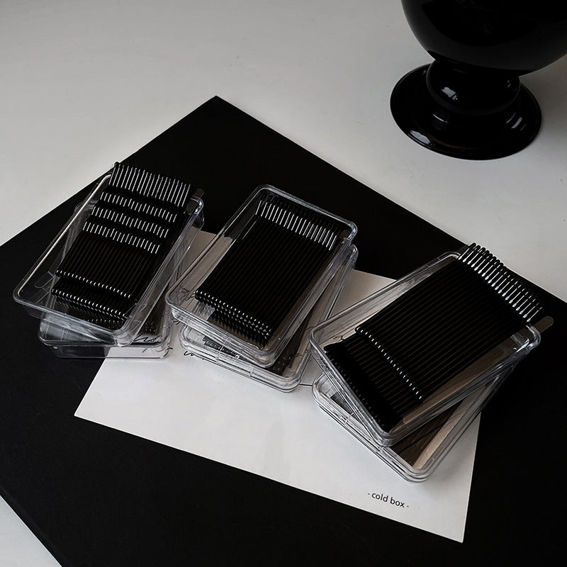 Black bobby pin packs displayed on white paper with 'cold box' text, modern beauty product presentation