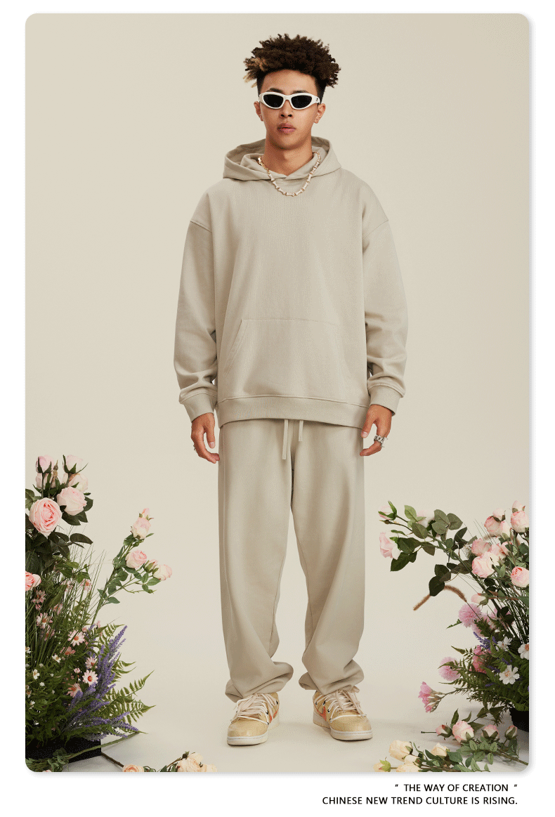 Man with twisted hair wearing beige hoodie and sweatpants with white sunglasses and silver chain