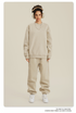 Model wearing cream sweatsuit set with oversized crew neck sweatshirt and loose-fit joggers, accessorized with cream headphones and silver necklace