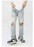 Model wearing light wash distressed jeans with knee rips, ankle zips, white tee and black/white sneakers on white backdrop