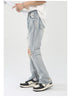 Side angle of light wash jeans showing distressed details and zip ankle opening, styled with black and white sneakers