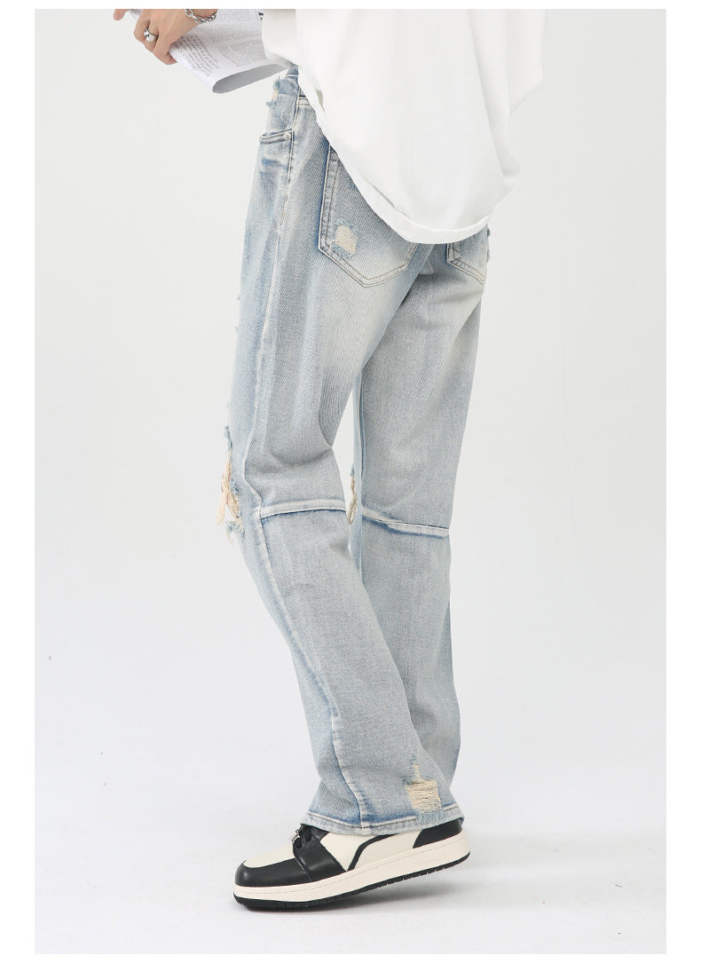 Side view highlighting ripped knee detail and straight leg silhouette of light wash jeans against white backdrop