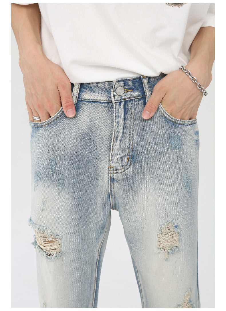 Detail shot of high-rise waistband and front pockets of distressed light wash jeans, paired with white t-shirt