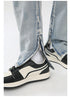 Close-up detail of silver ankle zip opening and white sock styling with black and cream retro sneaker