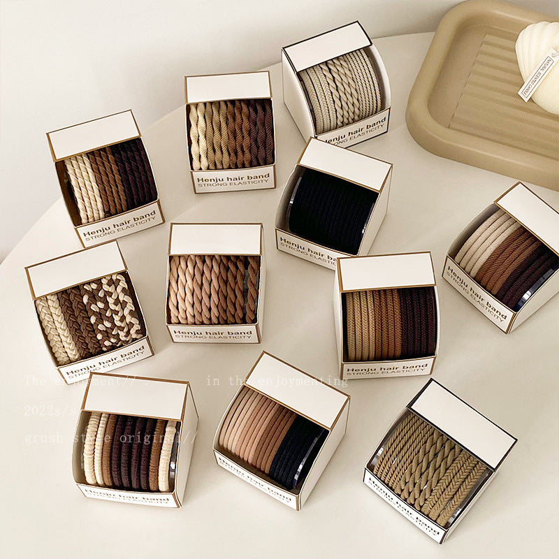 Multiple boxes of Henju hair bands in various neutral colors displayed on white surface, each labeled "Strong Elasticity"