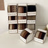 Stacked display of Henju hair band boxes showing different textures and colors including black, brown and beige, labeled "Strong Elasticity"