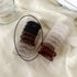 Two clear packages of spiral hair coils in various shades including black, brown and clear, displayed on white fabric