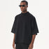 A model wearing black sunglasses and an oversized black mock neck t-shirt with dropped shoulders against a white backdrop