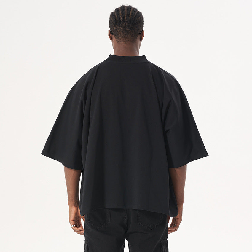 Back view of model with braided hair wearing black oversized t-shirt with mock neck collar and black cargo pants