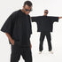 Split image showing model with hands in pockets and same model with arms outstretched wearing all-black streetwear outfit