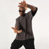 Model in black sunglasses making framing gesture wearing charcoal mock neck t-shirt and black pants against white background