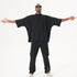 A model posing with arms outstretched wearing an oversized black t-shirt and black cargo pants with ankle zippers against white background